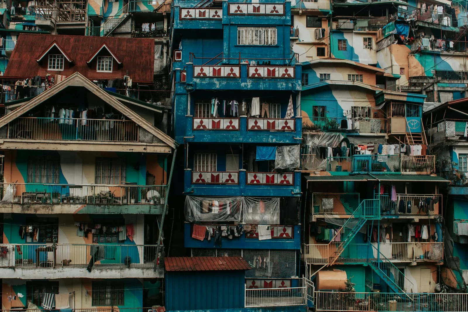 A densely packed, brightly painted multi-story apartment building with laundry hanging from balconies and iron grille windows.