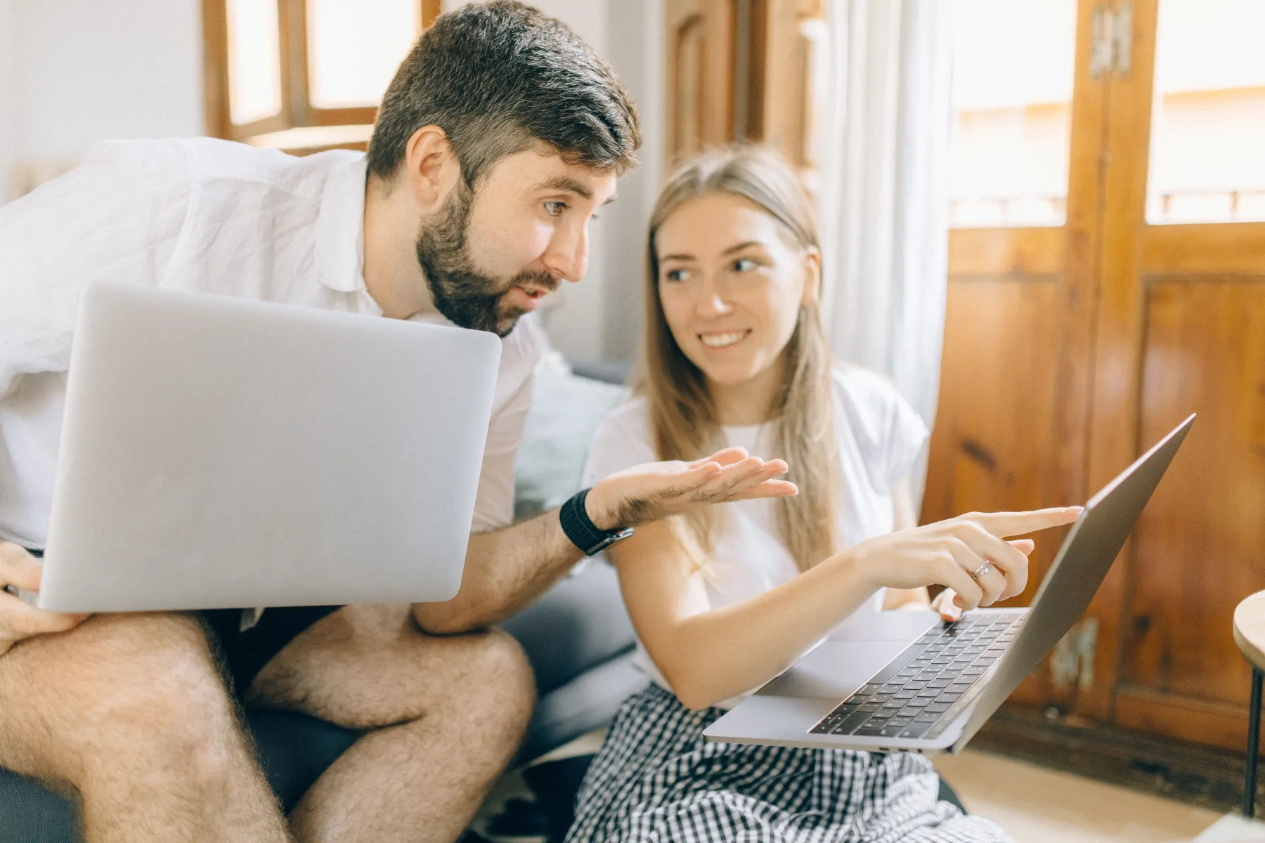 A man and woman sitting together, pointing at a laptop screen while discussing what's on it