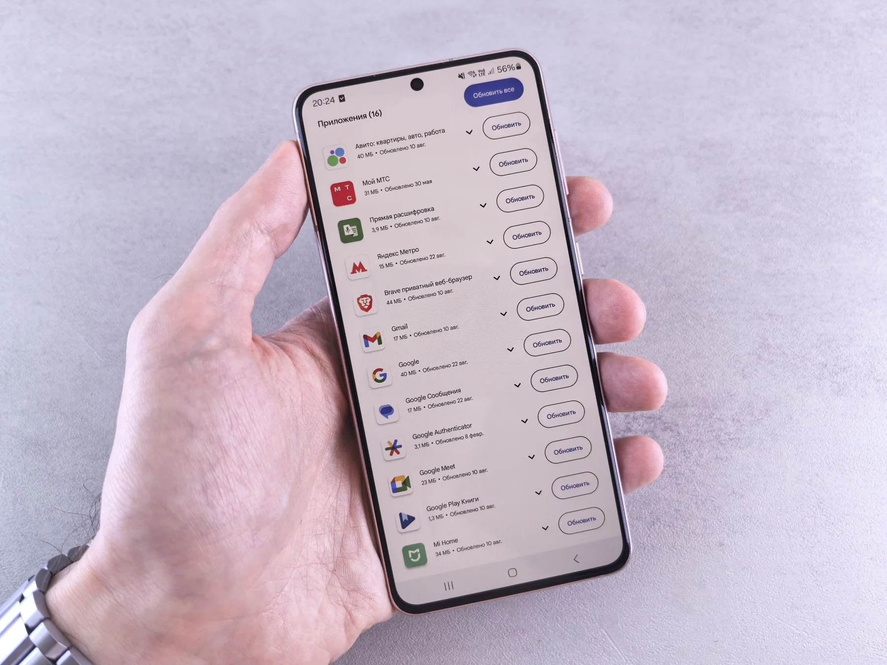 Hand holding a smartphone displaying a scrollable list of app entries