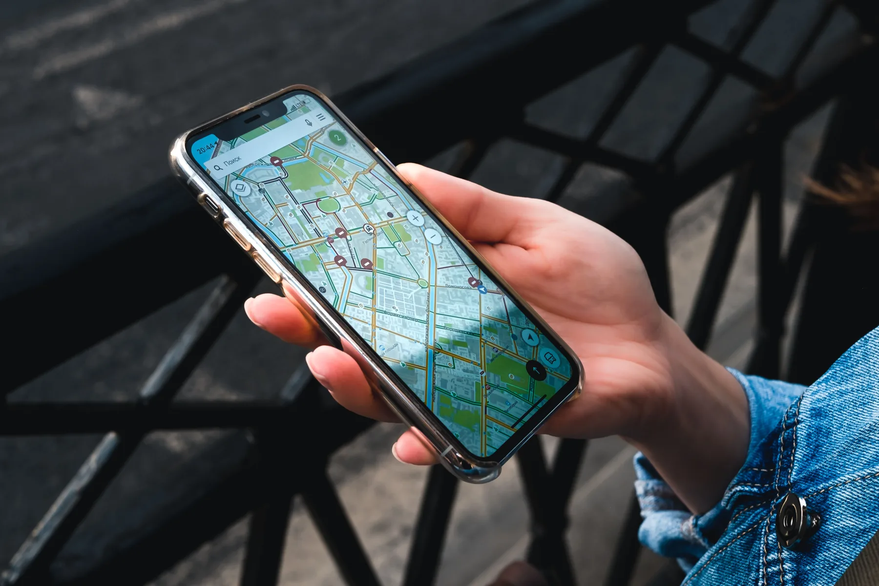 A hand holding a smartphone displaying a map app with a route drawn across city streets