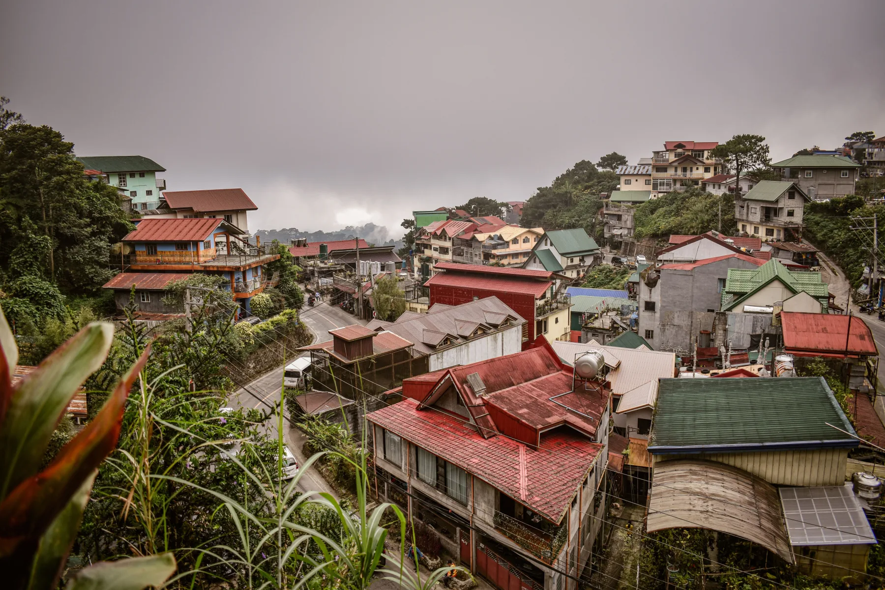Aerial view of a hillside neighborhood with houses of many different styles and roof colors