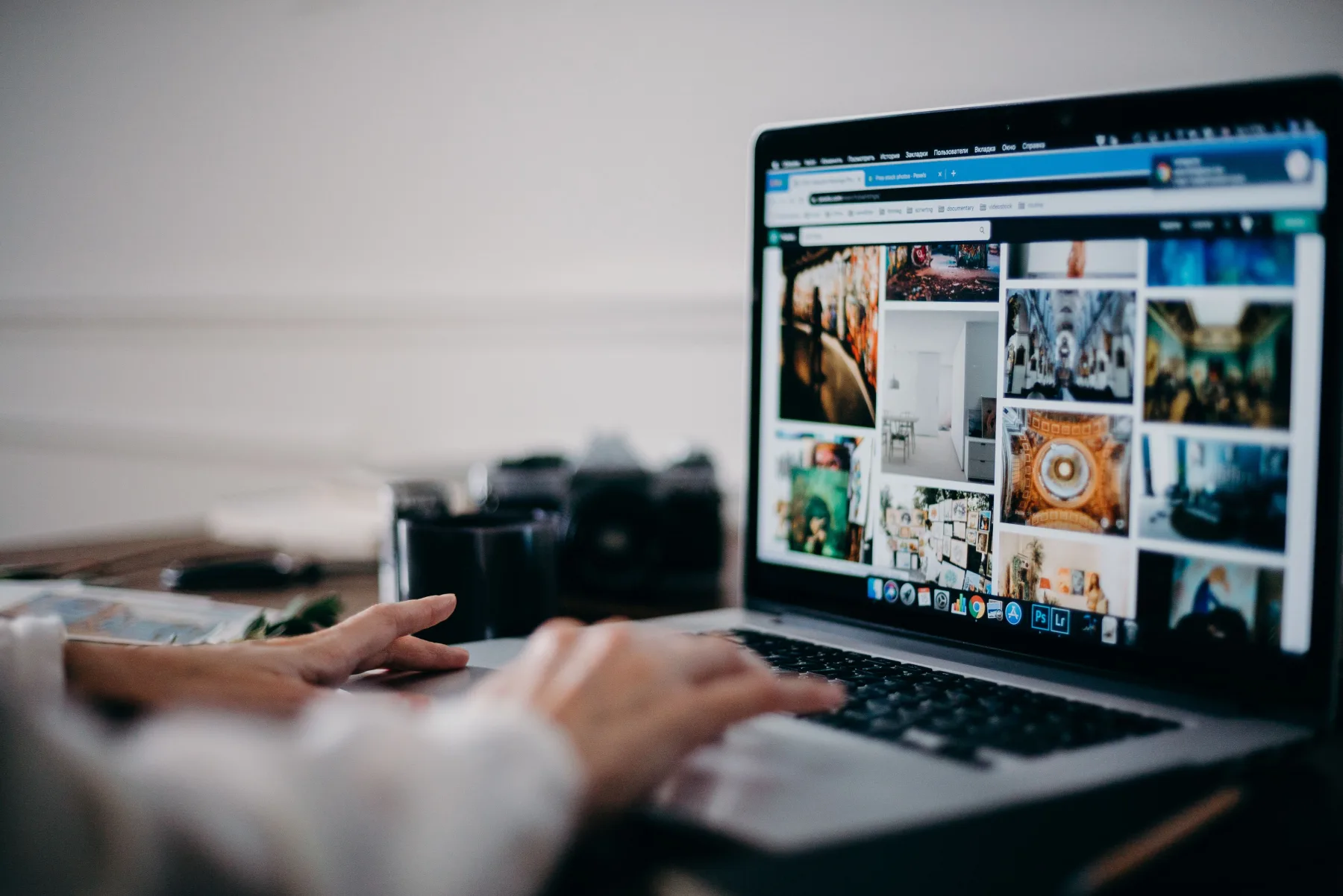 Person browsing a grid of interior and architecture photos on a laptop, with a camera resting nearby