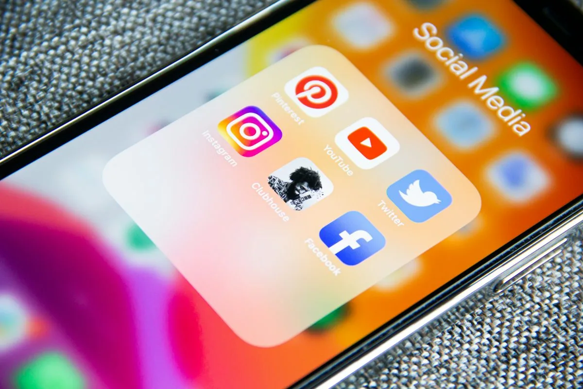 Close-up of a smartphone screen showing a folder labeled Social Media containing Instagram, Pinterest, YouTube, Twitter, Facebook, and Clubhouse app icons
