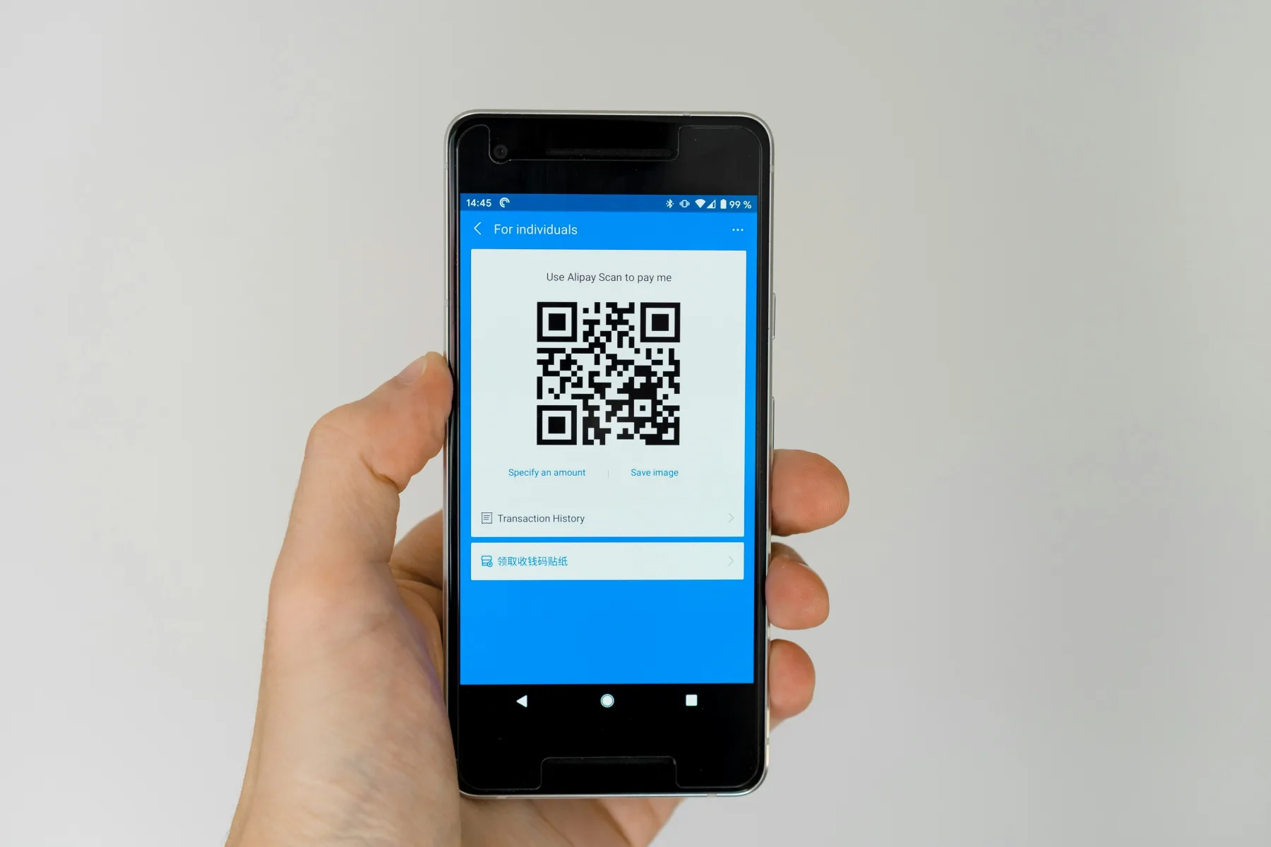 Close-up of a hand holding a smartphone displaying a QR code on a blue-themed app screen