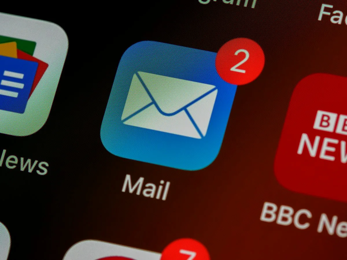 Close-up of a phone's home screen showing the Mail app icon with a red notification badge showing the number 2, next to a BBC News icon