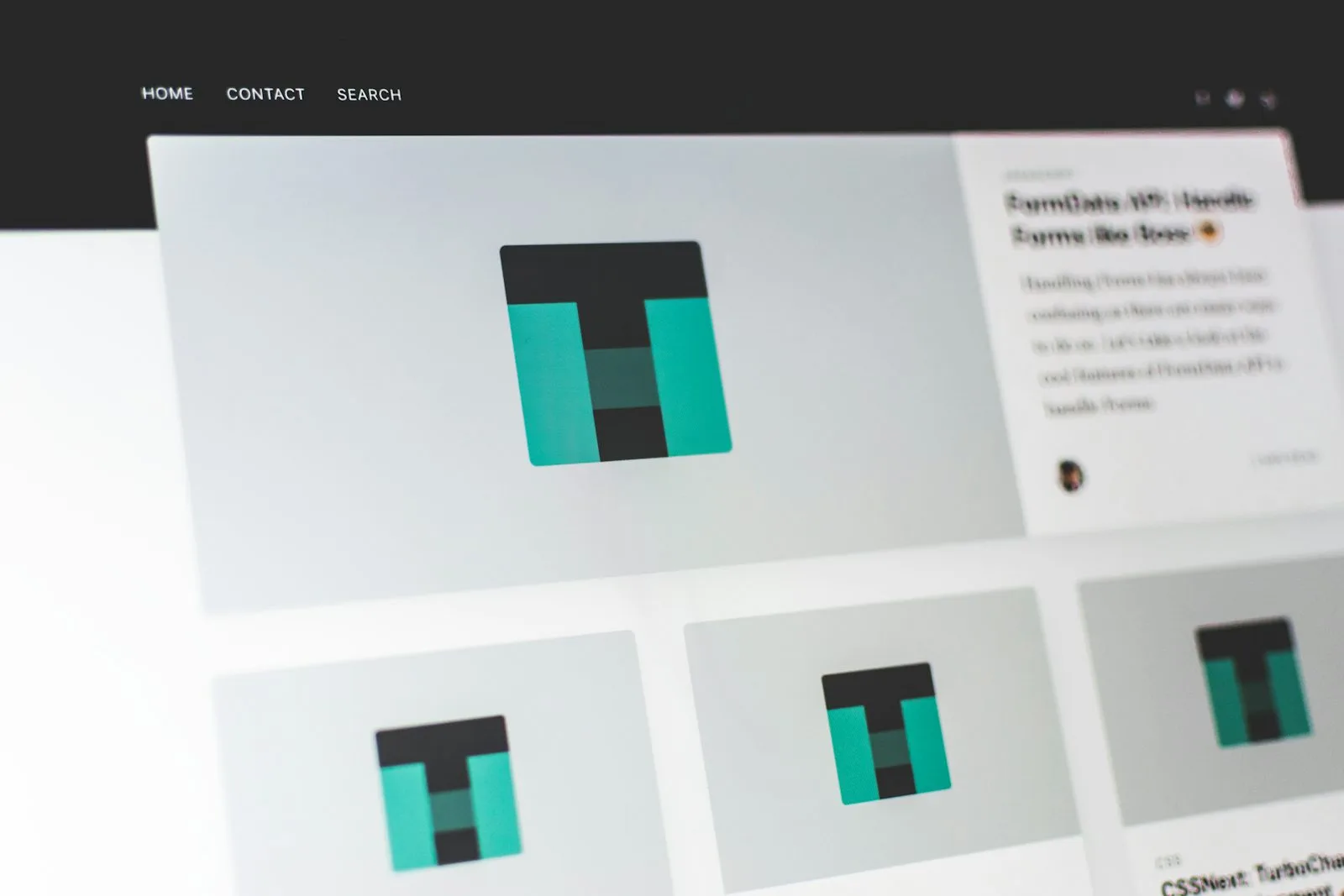 A tilted close-up of a blurred website homepage showing a grid of article cards under a dark navigation bar reading Home, Contact, Search