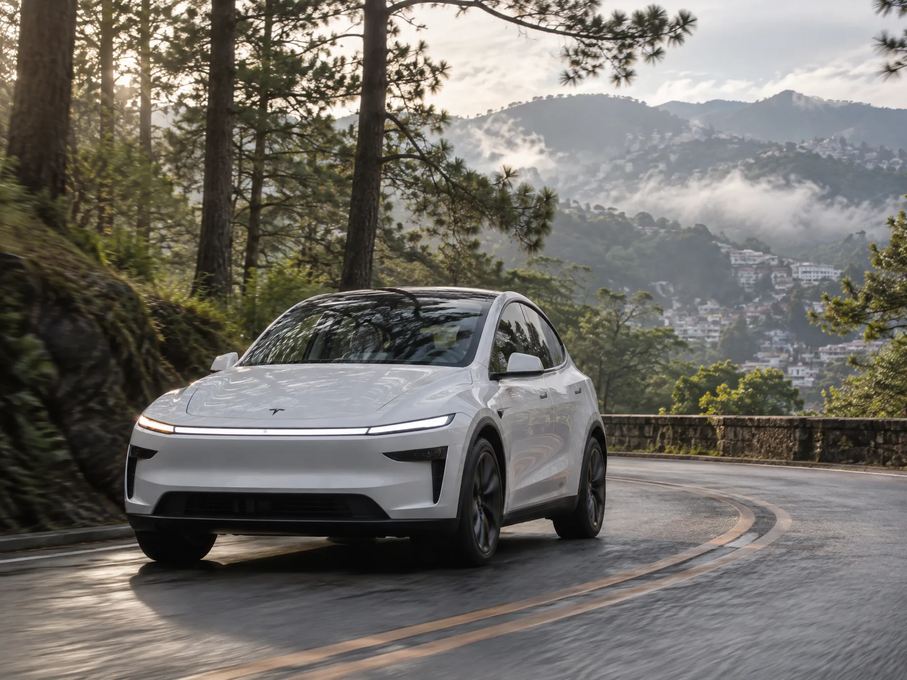 Tesla Model Y L driving a pine-lined mountain road above Baguio in morning mist