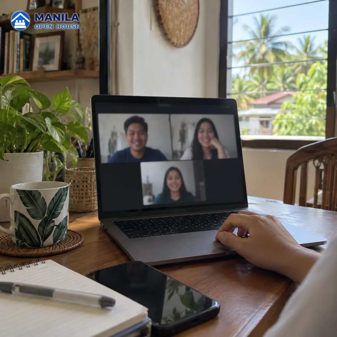 A laptop on a home desk showing a blurred video call with three people