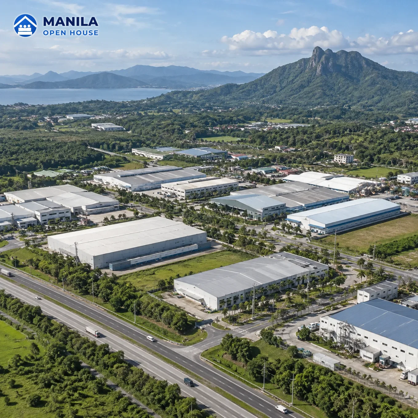 Aerial view of an industrial estate with warehouses, a highway, trees and a mountain behind